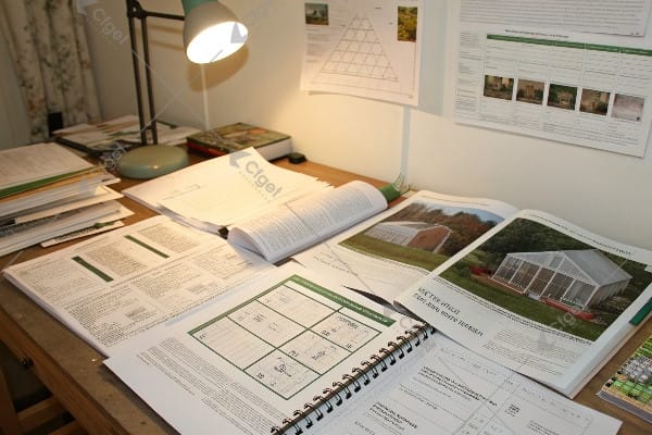 Grant proposal documents and greenhouse planning materials on desk
